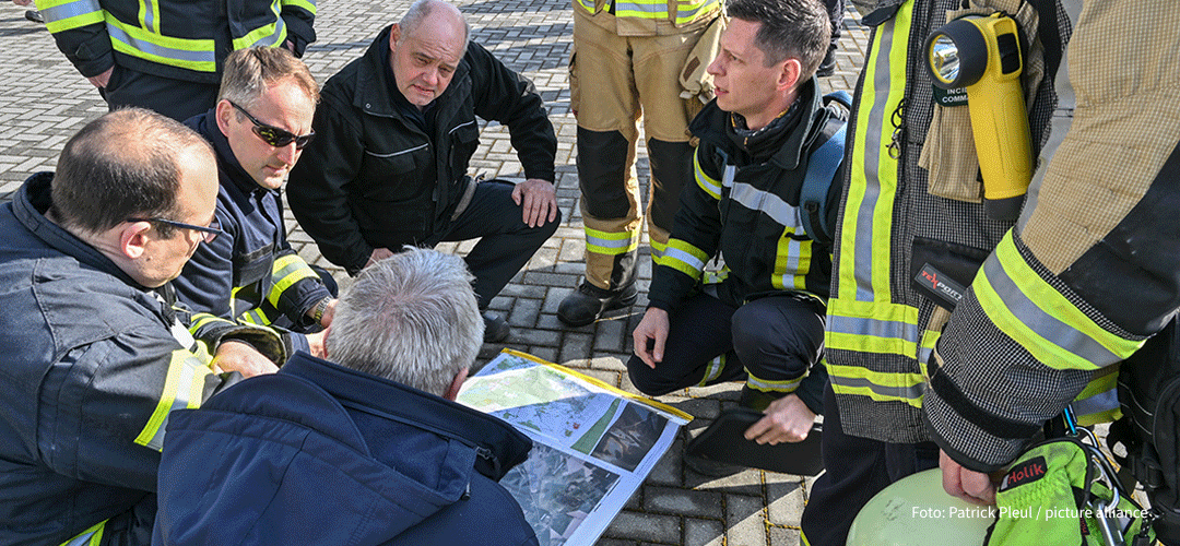 Einsatzkräfte der Feuerwehr bei Besprechung, Foto: picture alliance