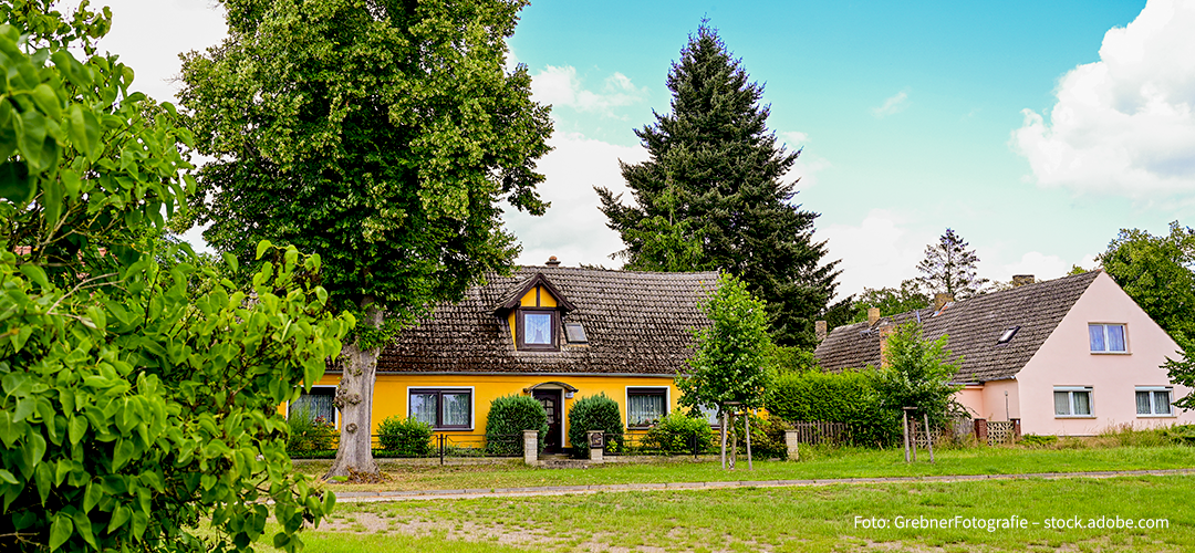 Zwei schöne Einfamilienhäuser mit Garten und Bäumen bei blauem Himmel im Sommer in Ketzür, Beetzseeheide