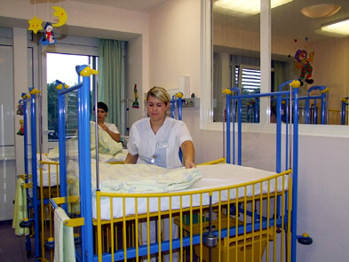 Foto: Zwei Auszubildende beziehen das Bettzeug der blau-gelben Bettchen.