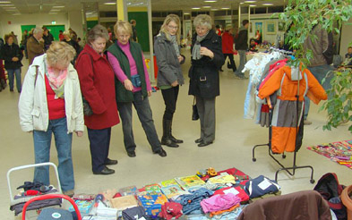 Foto: Frauen an einem Flohmarktstand mit Kindersachen und Spielzeug.