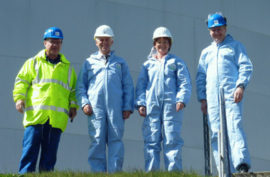 Foto: 4 Personen mit Schutzanzug und Helm vor dem Tank