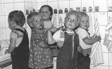 Schwarz-Weiß.Foto: 5 Krippenkinder beim Kämmen und Händeabtrocknen