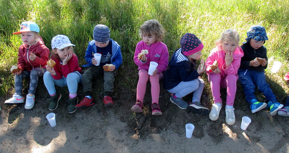 Foto: 7 Kinder sitzen in der Reihe mit Essen und Trinken