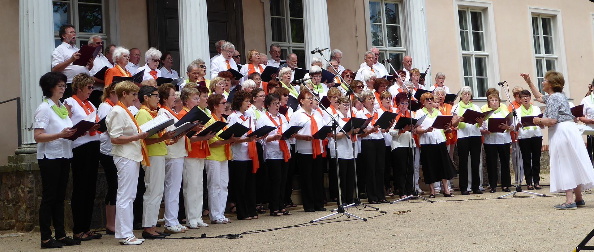 Foto: Sänger und Sängerinnen beim Singen mit Dirigentin