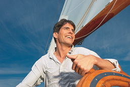 Foto: Mann am Steuerrad eines Segelbootes