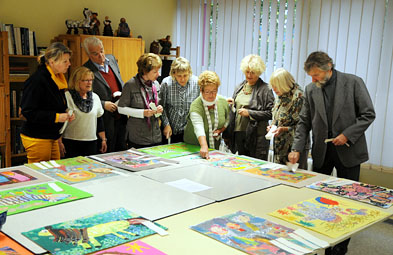 Foto: Jurymitglieder stehen um einen Tisch mit Zeichnungen herum.