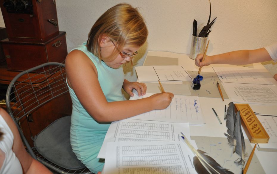 Mädchen schreibt mit Federkiel und Tinte
