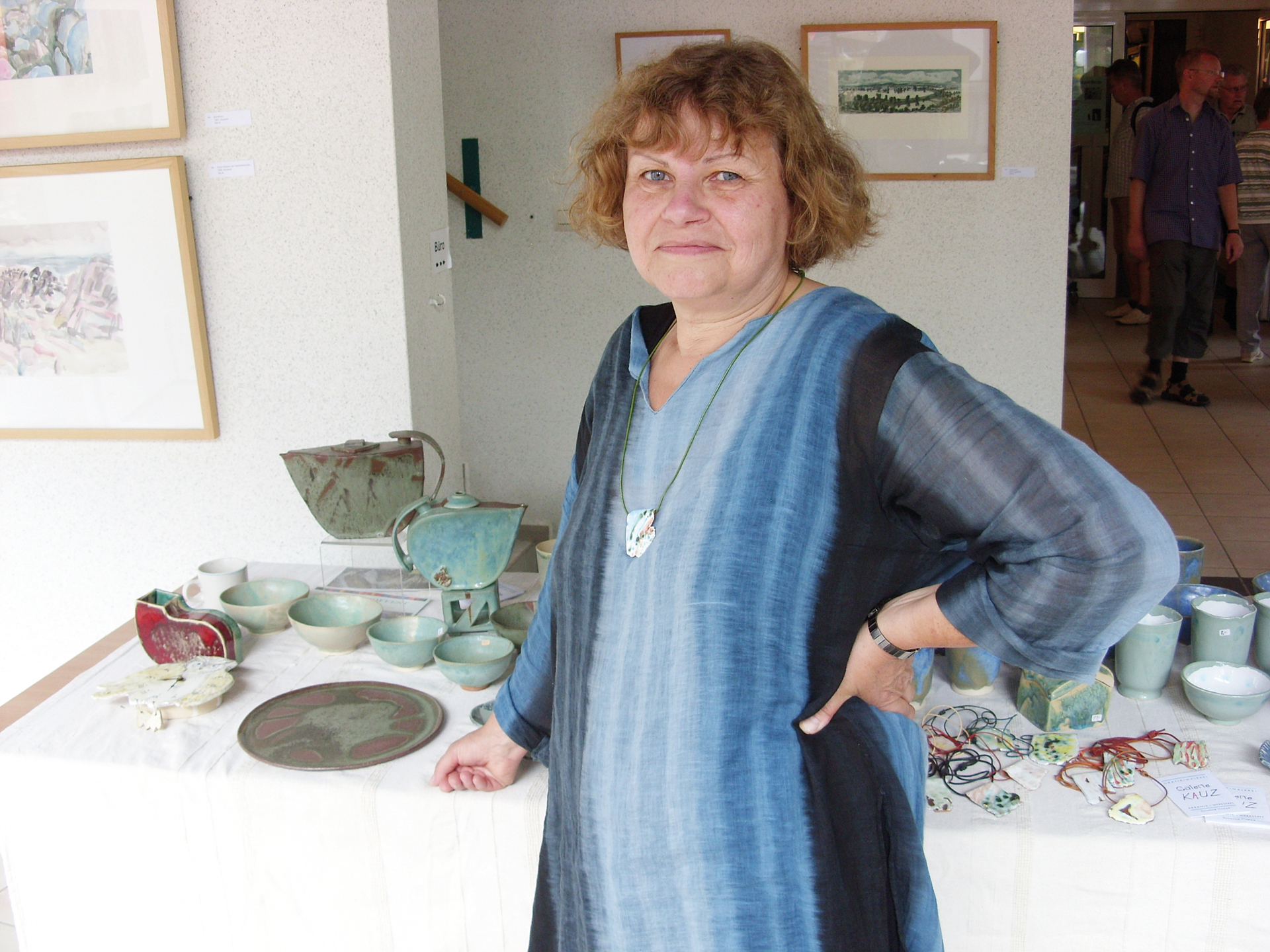 Foto: Künstlerin vor einem Tisch mit Keramikarbeiten