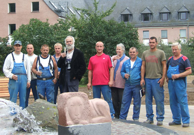 Foto: Künstler und Bauarbeiter vor dem Brunnen