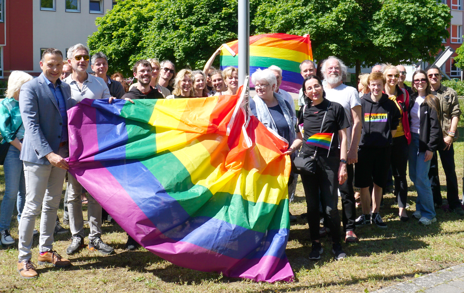 Foto: Gruppenfoto mit Regenbogenfahne