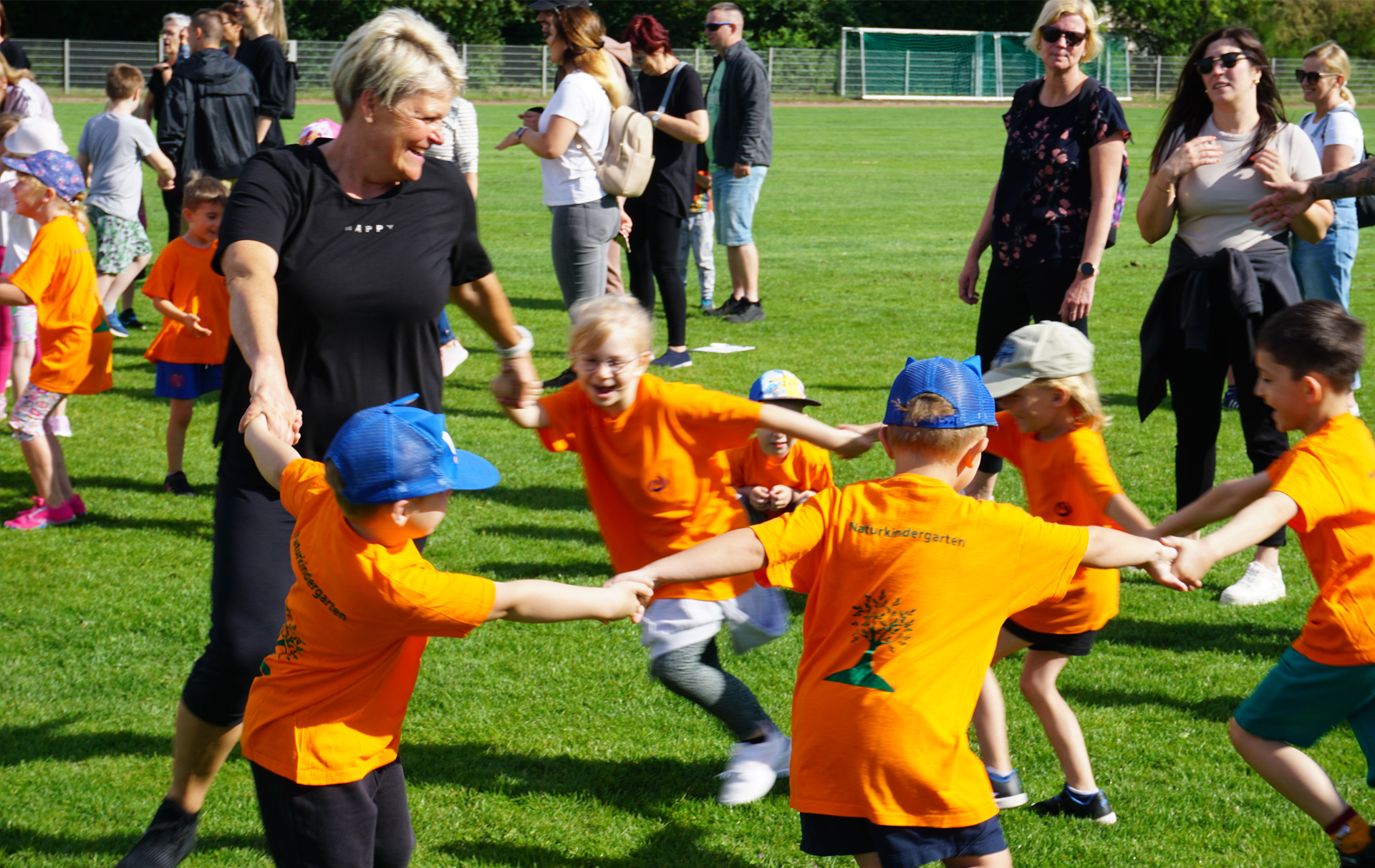 Foto: Kinder mit Erzieherin laufen zusammen im Kreis.