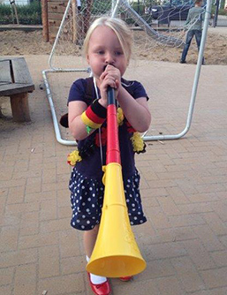 Foto: Grundschülerin mit Fußballtröte