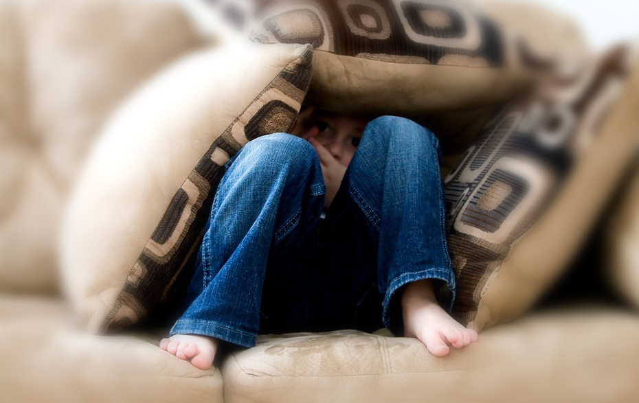 Foto: ängstlicher Junge versteckt sich unter Kissen