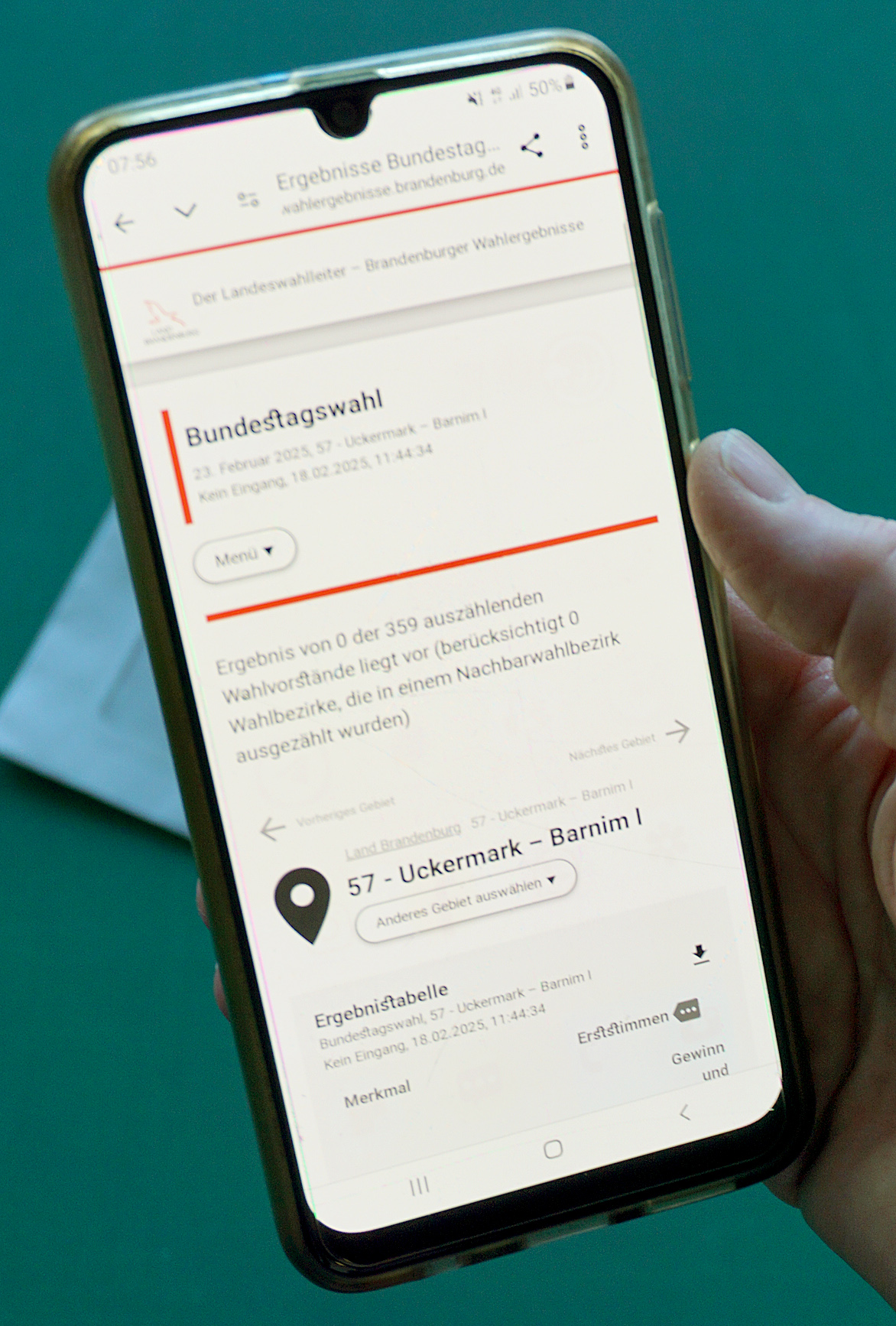 Foto: Hand mit Smartphone, auf dem das Wahlportal angezeigt wird.
