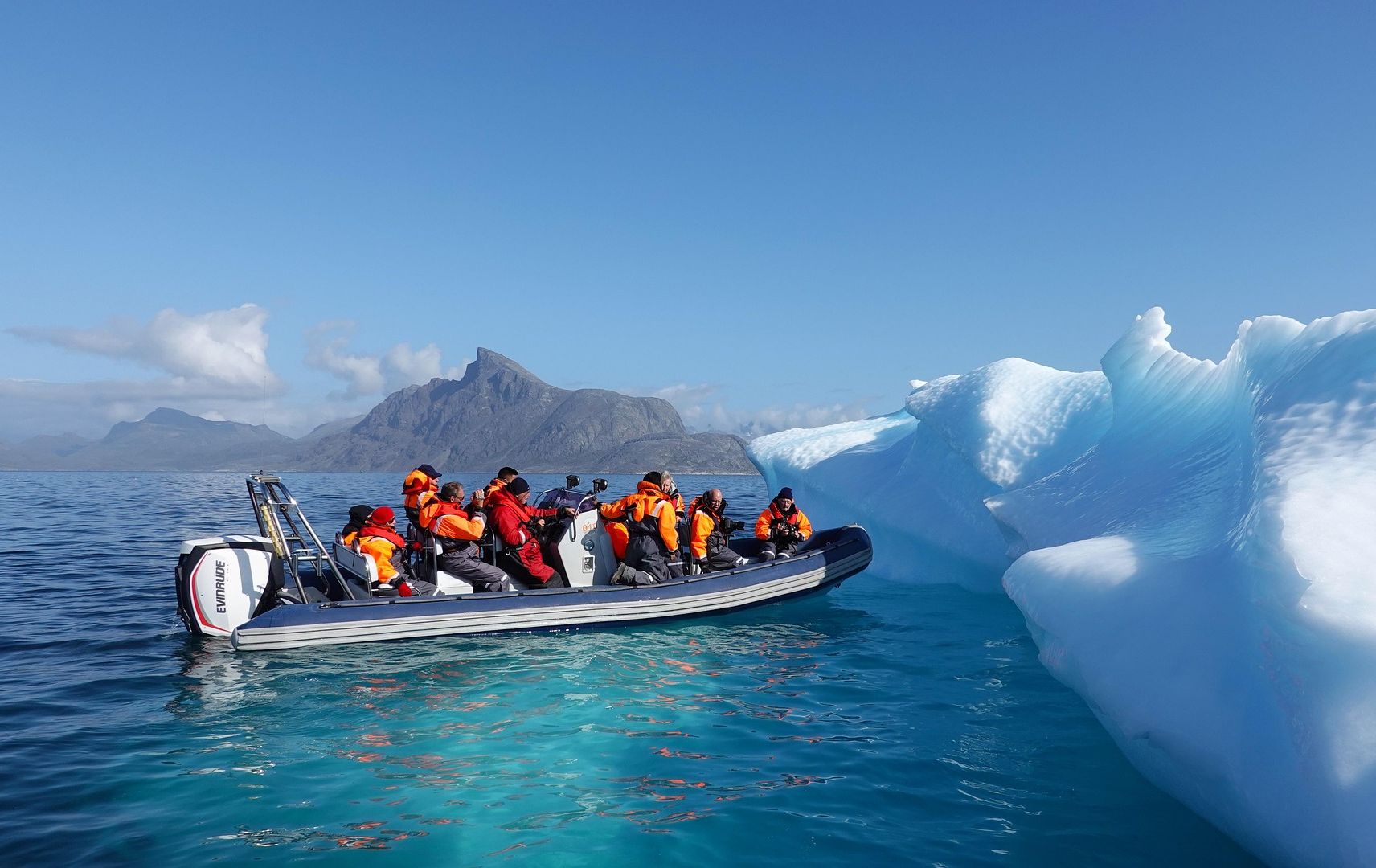 Foto: Boot mit mehreren Personen nähert sich einem Eisberg