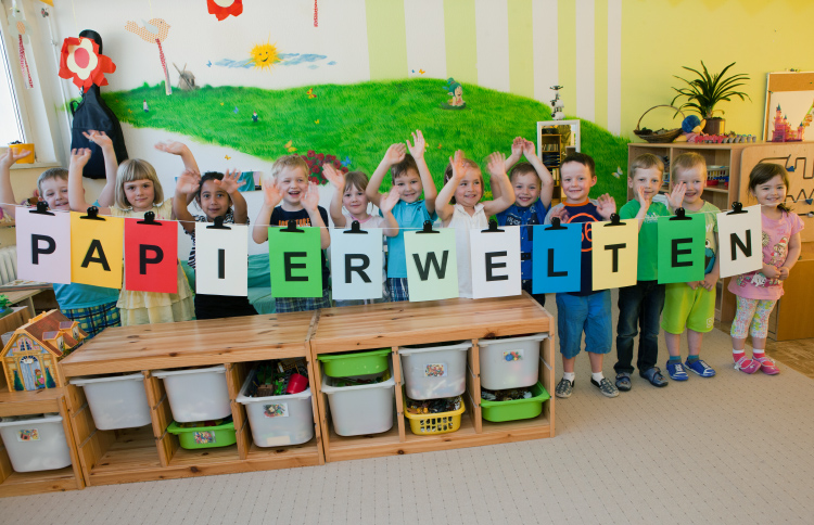 Foto: Kinder hinter einer Wäscheleine mit Papierbögen mit einzelnen Buchstaben