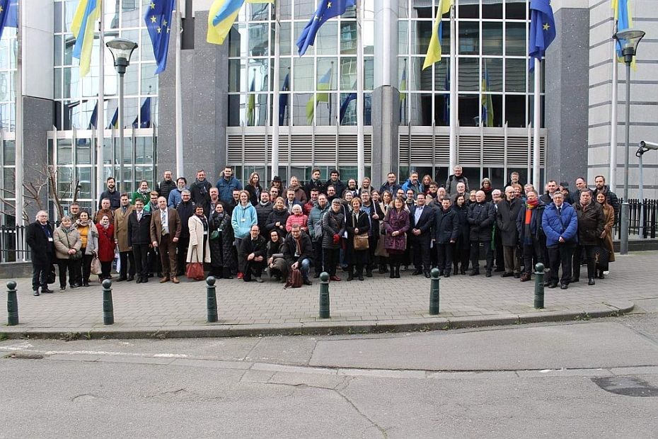 Eine sehr große Menschengruppe vor dem Gebäude des europäischen Parlaments im Hintergrunf  EU-Fahnen und Ukraine-Fahnen im Wechsel