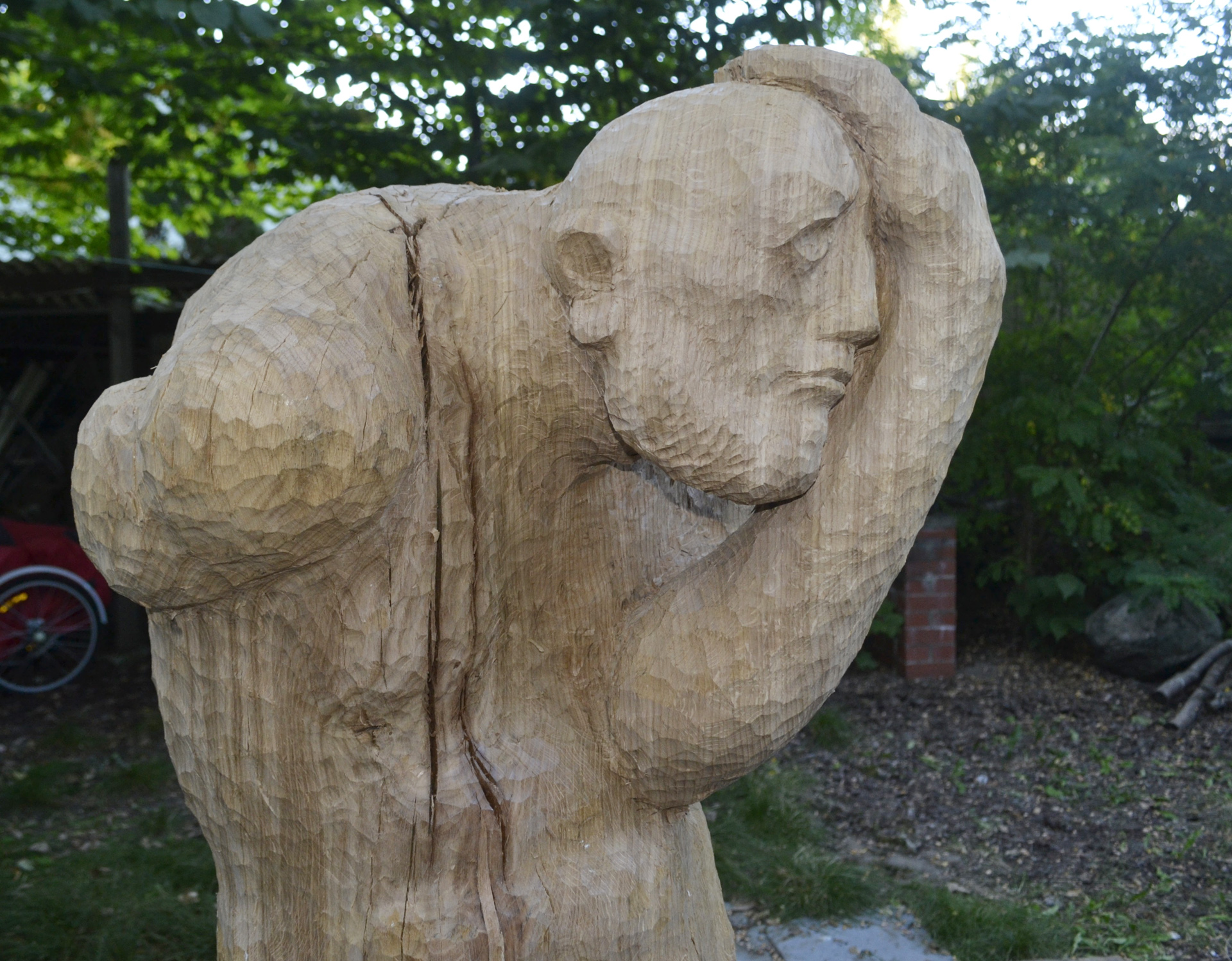 Foto: Holzskulptur zeigt eine gekrümmt stehenden alten Mann, der mit einem Arm seinen Kopf umfasst