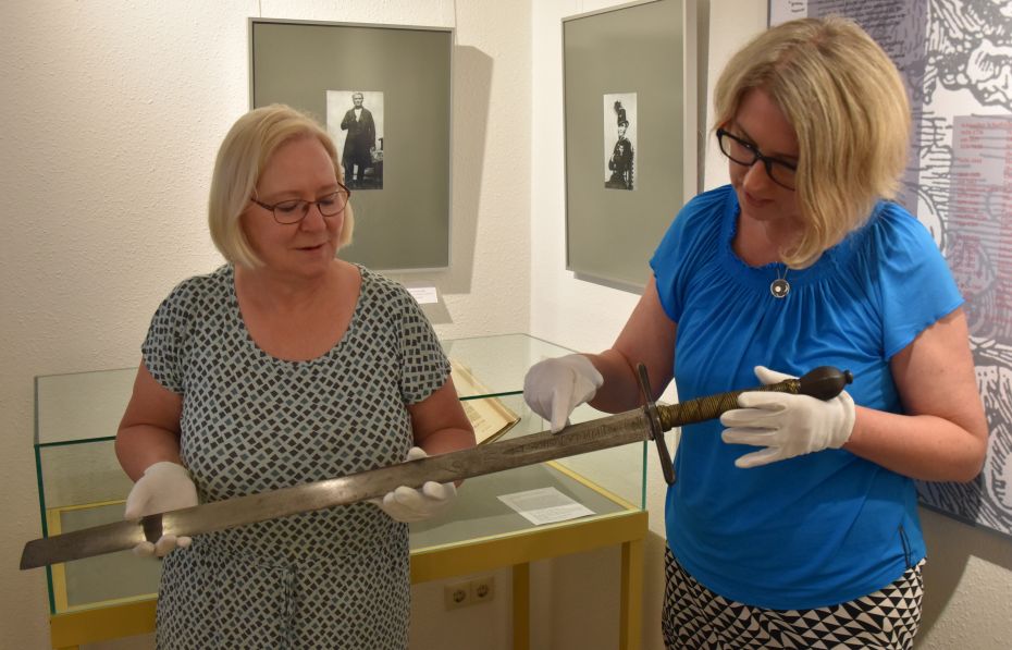 Zwei Frauen halten ein Schwert in den Händen.