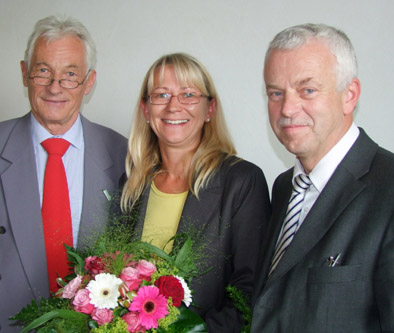 Foto: Porträt der drei Personen mit Blumenstrauß