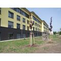 Foto: Neubau mit gelber Fassade und neugepflanzten Bäumen davor