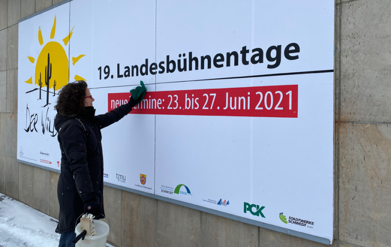 Foto: Eine Frau überklebt ein Plakat. Foto: Eine Frau überklebt ein Plakat.