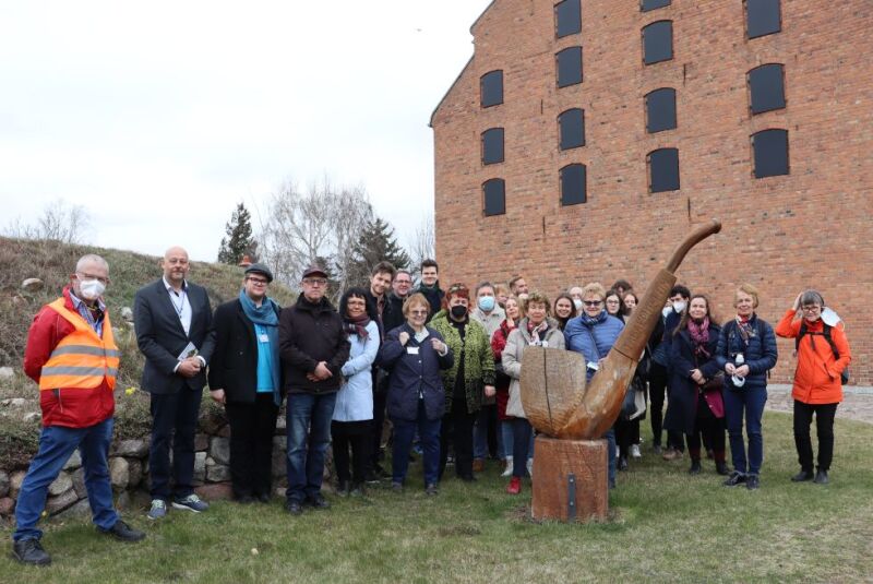 Gruppenfoto mit über 20 Menschen, im Hintergrund ist das Gebäude des Museums