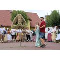 Auf dem Marktplatz von Vierraden steht mittig eine Erntekrone aus Tabakblüten. Rechts tanzt die Tabakkönigin Luisa Müller mit ihrem Freund einen Walz. Im Hintergrund stehen Menschen in Hugenotten-Kostümen. 