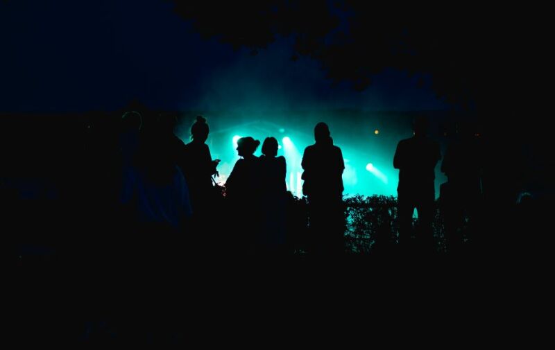 Menschengruppe im Dunkeln im Hingtergrund erhellt ein Feuerwerk den Nachthimmel