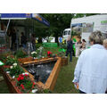 Foto: Stand mit Springbrunnen und Holzblumenkästen