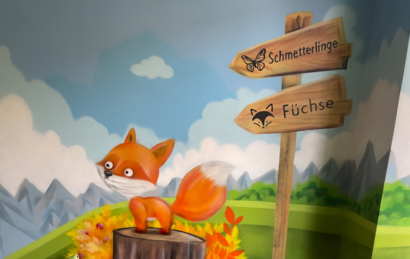 Foto: Wandbild mit Fuchs auf einem Baustamm und Wegweiser in freundlicher Landschaft