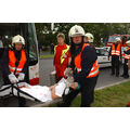 Foto: Zwei Feuerwehrkräfte tragen ein bewusstloses Opfer aus dem Bus