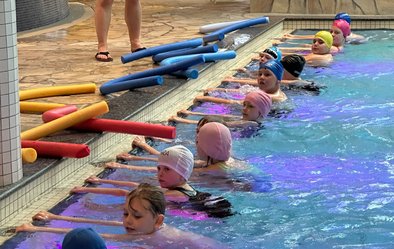 Foto: Kinder halten sich im Wasser am Beckenrand fest Foto: Kinder halten sich im Wasser am Beckenrand fest