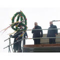 Foto: Bürgermeister, Vereinschef und Zimmerermeister stehen auf dem Dach bei der Richtkrone.