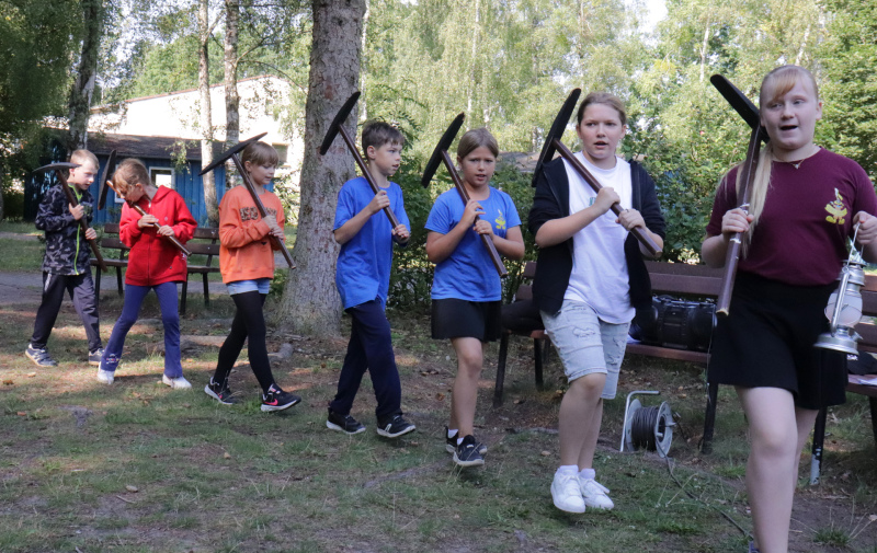 Foto: 7 Kinder mit Werkzeug laufen hintereinander