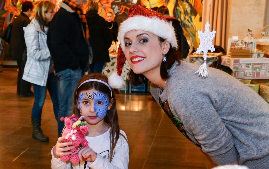 Foto: Frau mit Weihnachtsmütze und geschminktes Kind beim Martinsmarkt